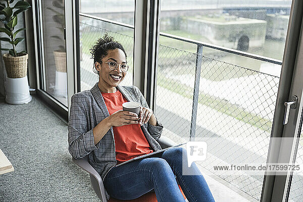 Smiling businesswoman with coffee cup at work place
