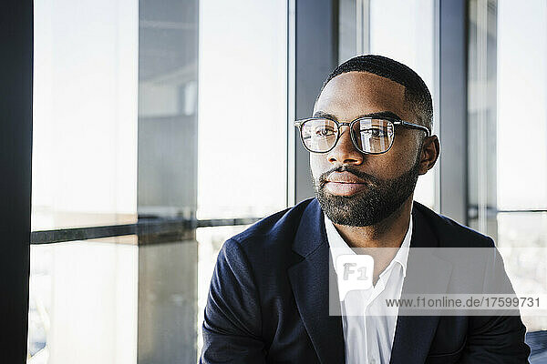 Contemplative businessman with eyeglasses in office