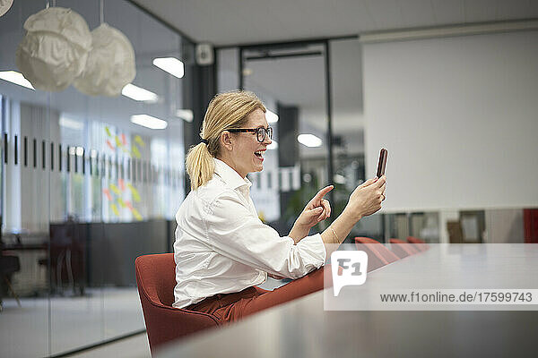 Happy businesswoman on video call through smart phone in office