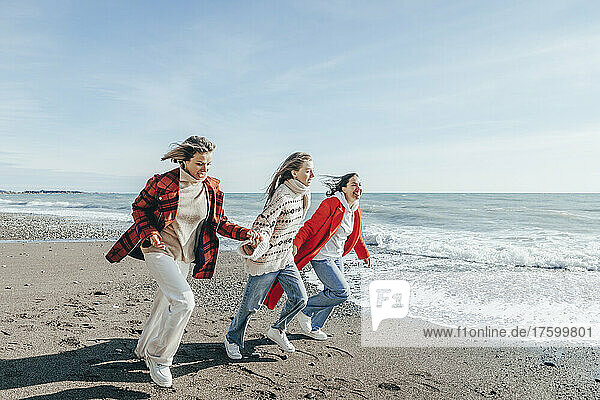 Friends running on sand at seashore