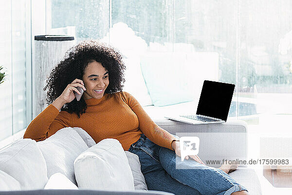 Smiling woman talking on mobile phone in living room