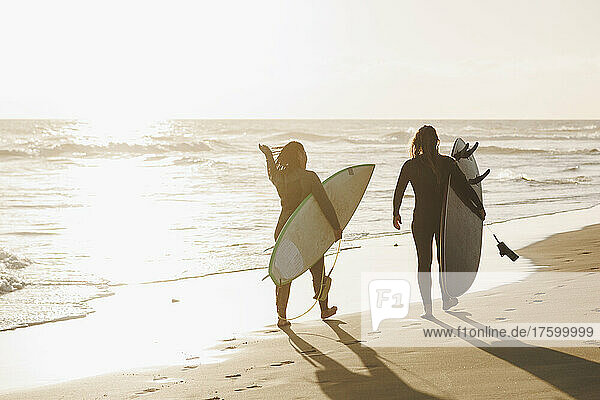 Women with surfboards walking at beach on sunset  Gran Canaria  Canary Islands