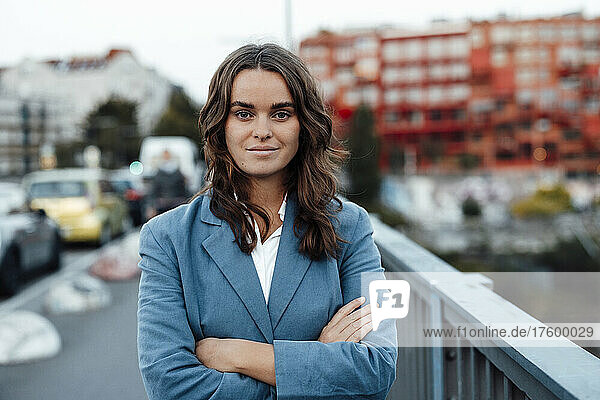 Young businesswoman with arms crossed standing on bridge