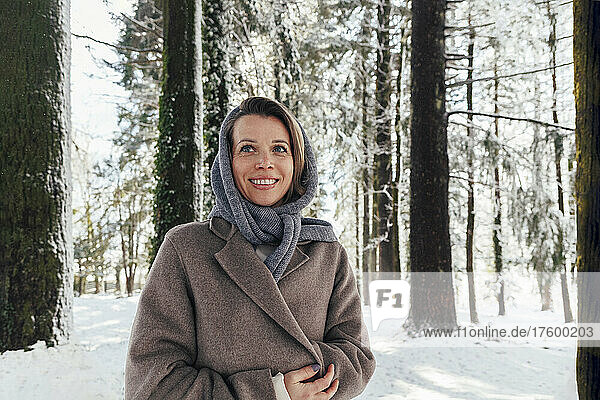 Smiling woman standing in winter forest