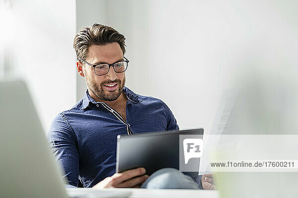 Businessman wearing eyeglasses using tablet PC at office