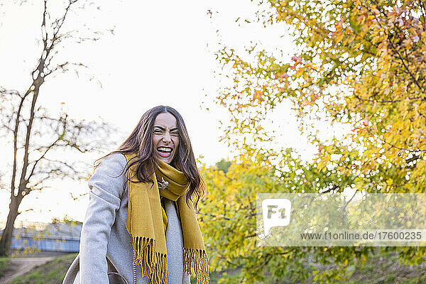 Cheerful young woman standing in autumn park