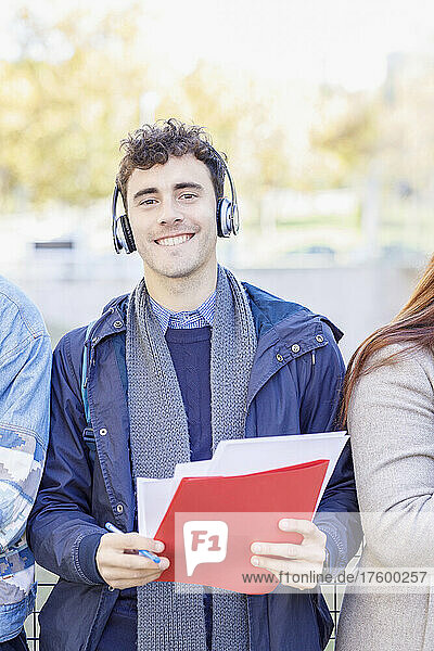 Smiling man listening music through headphones on campus