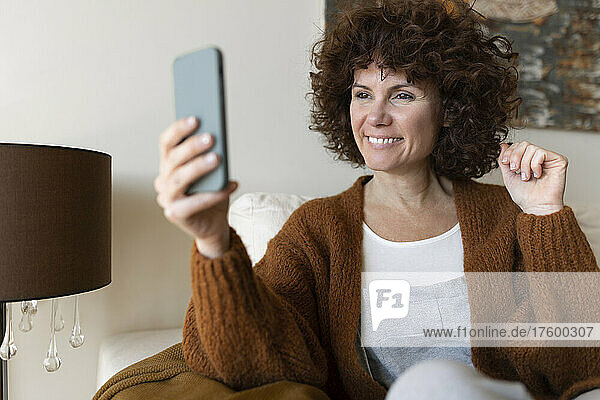 Happy woman on video call through mobile phone in living room