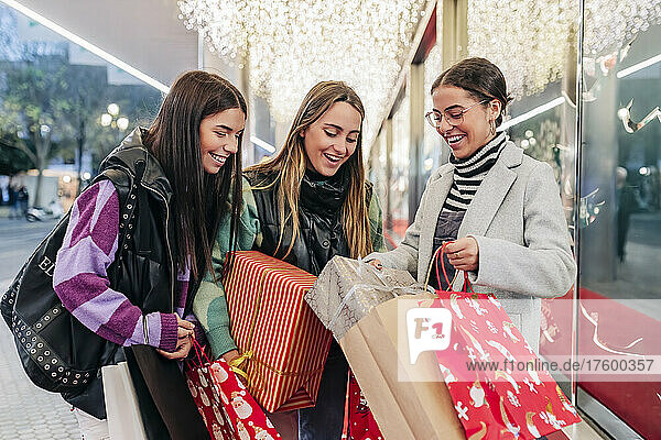 Smiling woman showing gift to friends at Christmas