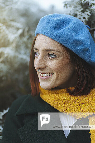 Happy redhead woman in blue beret and yellow scarf