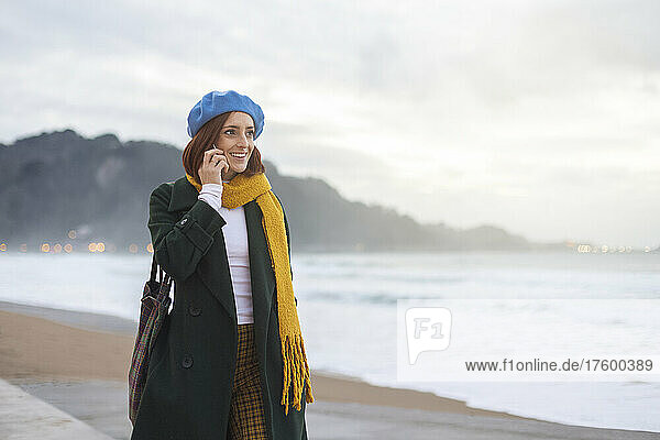 Frau spricht mit dem Smartphone und geht am Ufer entlang