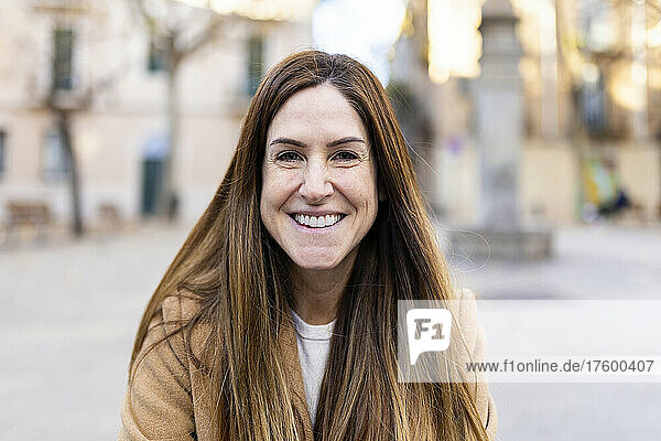 Happy woman with long brown hair in city
