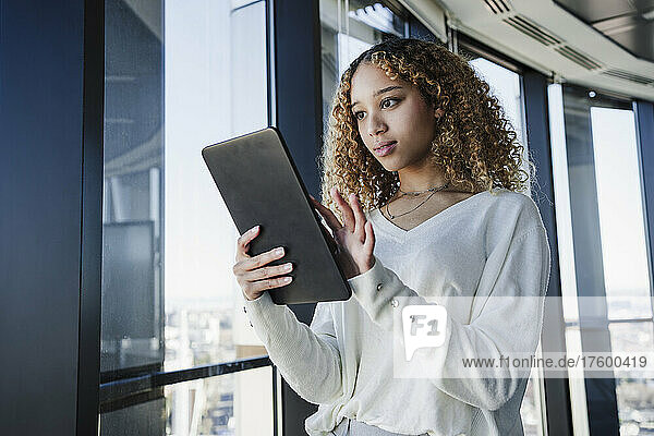 Geschäftsfrau mit lockigem Haar nutzt Tablet-PC im Büro