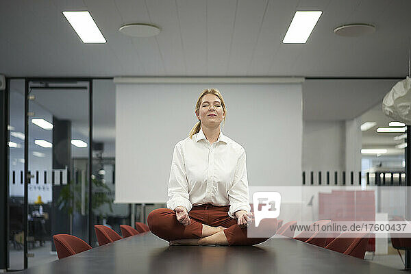 Businesswoman meditating in meeting room