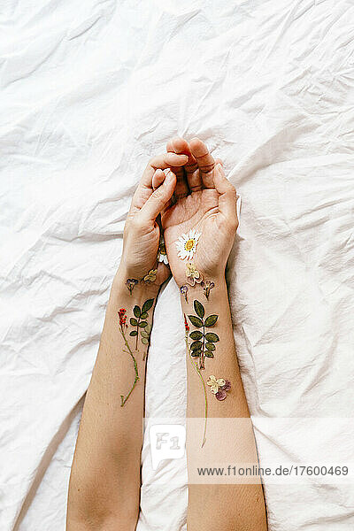Woman's hands with flowers arrangement on bed