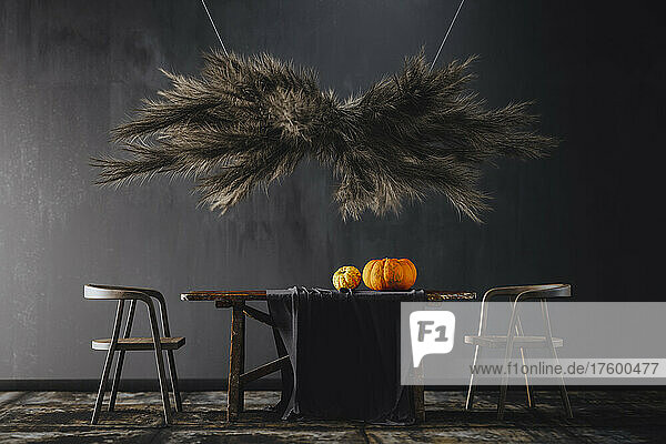 Three dimensional render of pampas grass hanging over wooden table with pumpkins on top