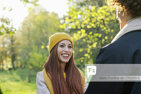 Lächelnde rothaarige Frau beim Liebesspiel mit ihrem Freund im Park