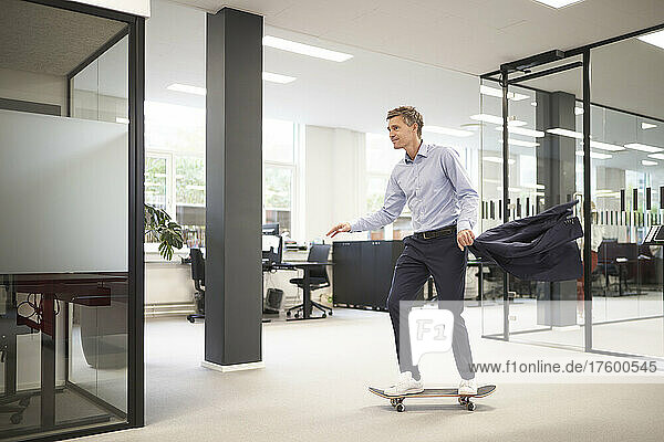 Businessman skateboarding in modern office