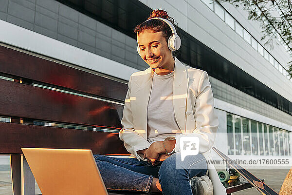 Lächelnde Frau mit Kopfhörern bei Videoanruf im Park