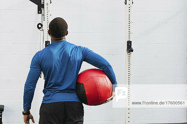 Athlete holding medicine ball in front of wall in gym