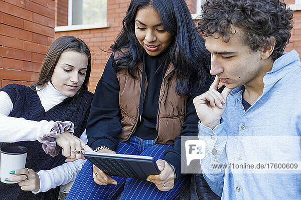 Woman sharing tablet PC with friends on university campus