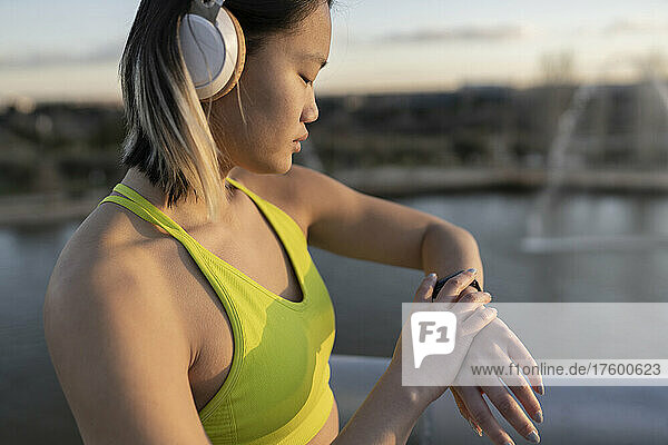 Young athlete with headphones checking time on wristwatch