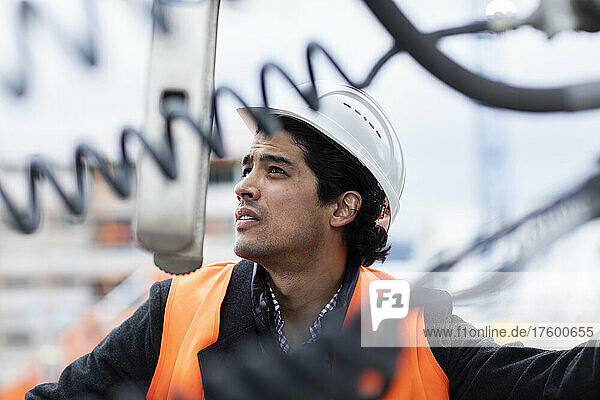 Engineer wearing hardhat examining machinery outdoors