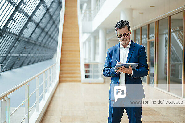 Businessman using tablet PC standing at office