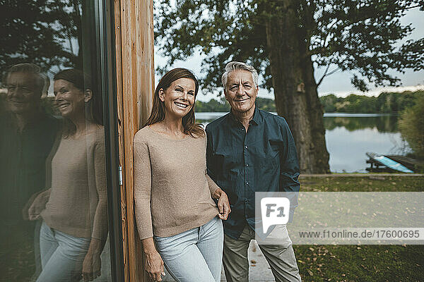 Glückliche Frau mit älterem Mann  der an der Glaswand im Hinterhof steht