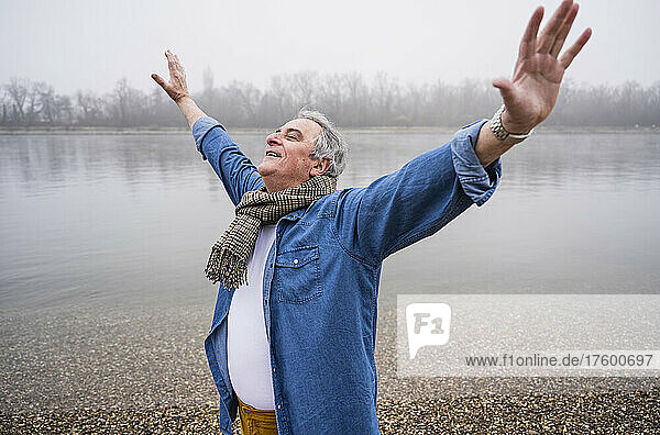 Senior man standing with arms outstretched at beach