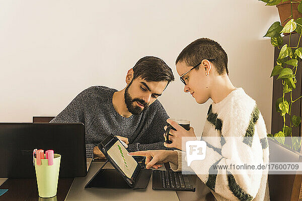 Businesswoman showing graph on digital PC to businessman in office