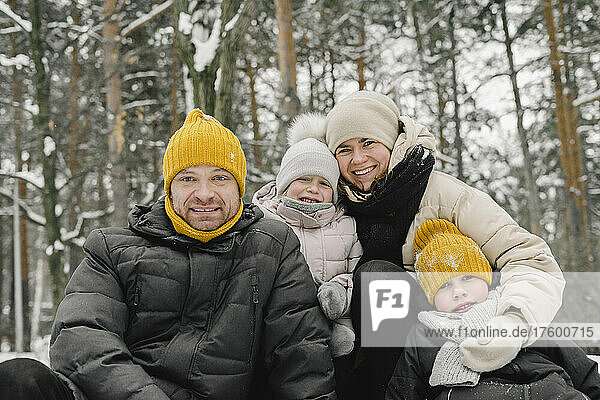 Smiling man and woman with daughter and son in winter forest