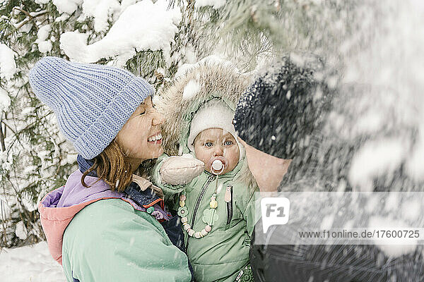 Woman carrying daughter by man playing with snow in winter