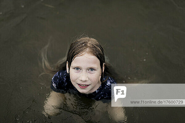 Mädchen mit braunen Haaren schwimmt im Seewasser