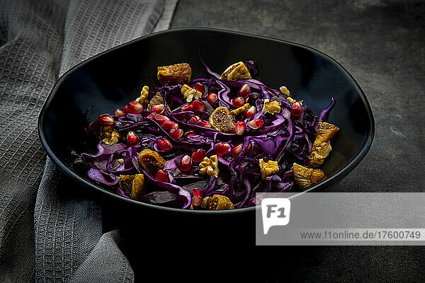 Studio shot of bowl of vegan salad with red cabbage  pomegranate seeds  dried figs and walnuts