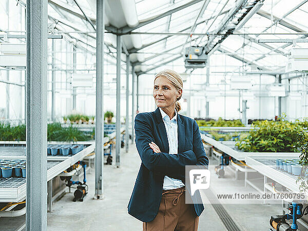 Confident biologist with arms crossed at plant nursery