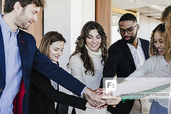 Multi-ethnic business colleagues stacking hands in coworking office