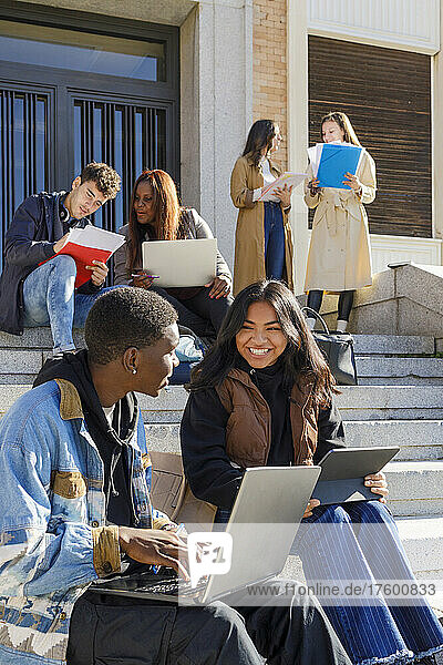 Multiracial college students studying on steps on campus