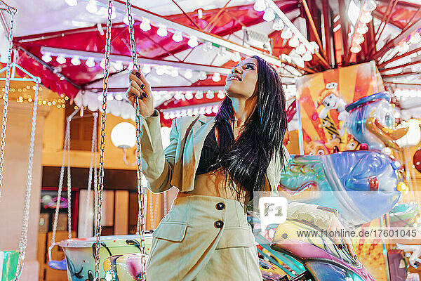 Young woman looking at merry-go-round in amusement park