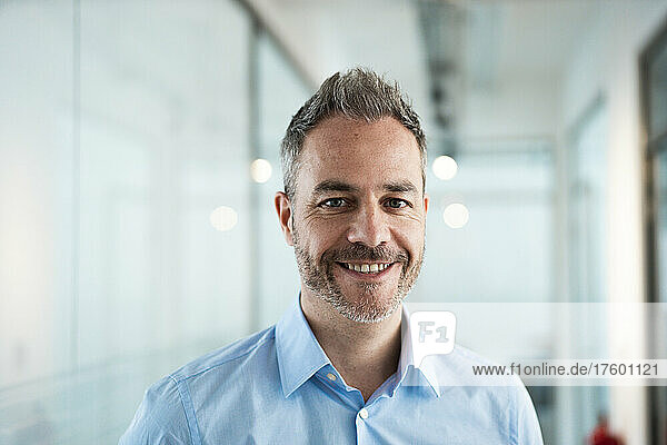 Smiling businessman with stubbles in office corridor