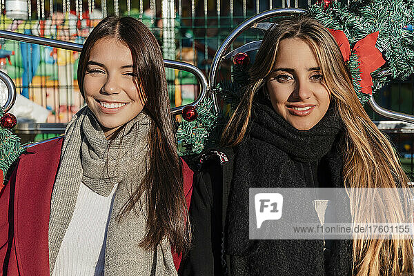 Smiling young friends with long hair wearing warm clothing on sunny day