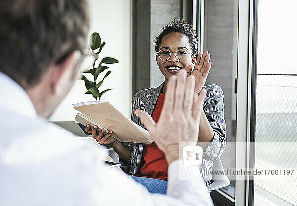 Multiracial colleagues giving high-five at work place