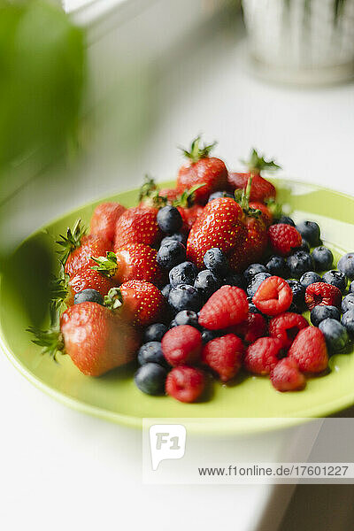 Plate of blueberries  raspberries and strawberries on table