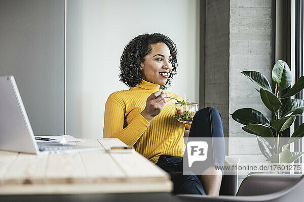 Contemplative businesswoman having salad in office