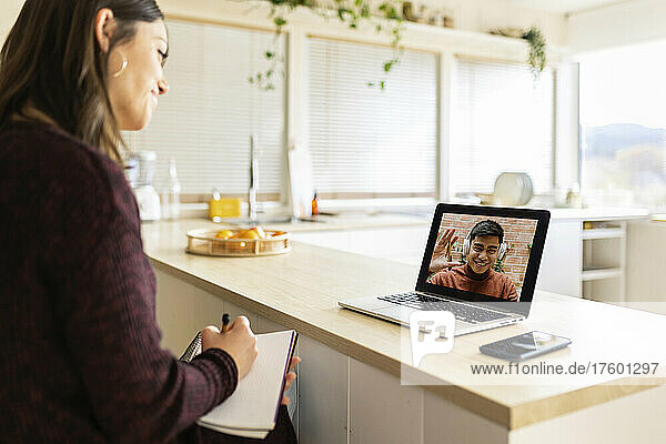 Businesswoman doing video call with colleague on laptop at home
