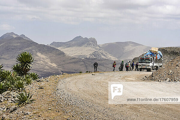 Menschen stehen auf dem Rücksitz eines Lastwagens und am Straßenrand in den Simien-Bergen im ländlichen Äthiopien  Semien-Nationalpark; Äthiopien