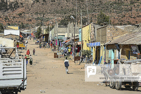 Dorf im ländlichen Äthiopien und Fußgänger auf einem von Gebäuden gesäumten Feldweg; Äthiopien