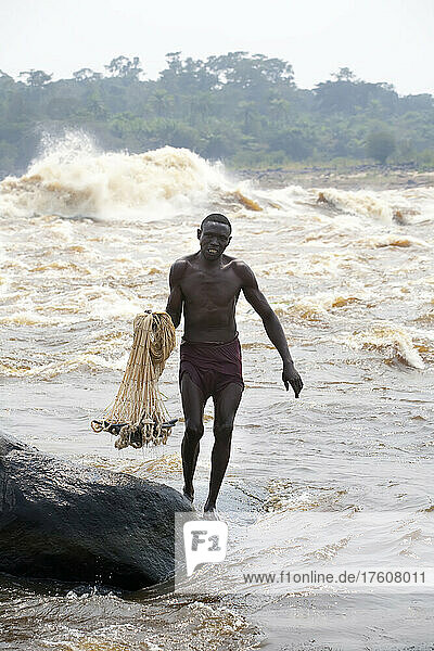 A Congolese fisherman prepares to throw his net from the shoreline.; Congo River  Kinshasa  Democratic Republic of the Congo.