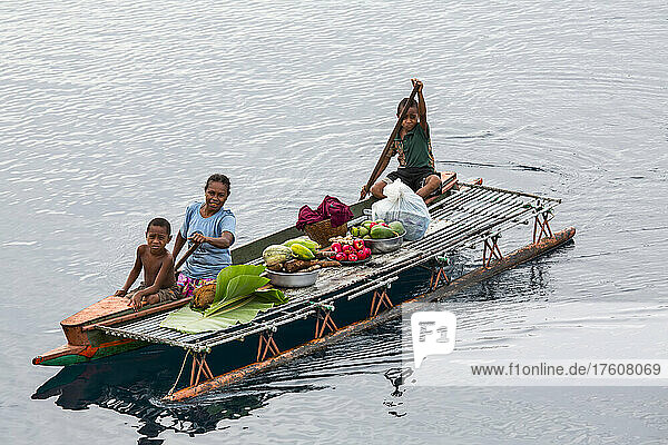 Einheimische Familie verkauft Früchte vom Kanu aus in der Sewa Bay in der China Strait von Papua-Neuguinea; Provinz Milne Bay  Papua-Neuguinea