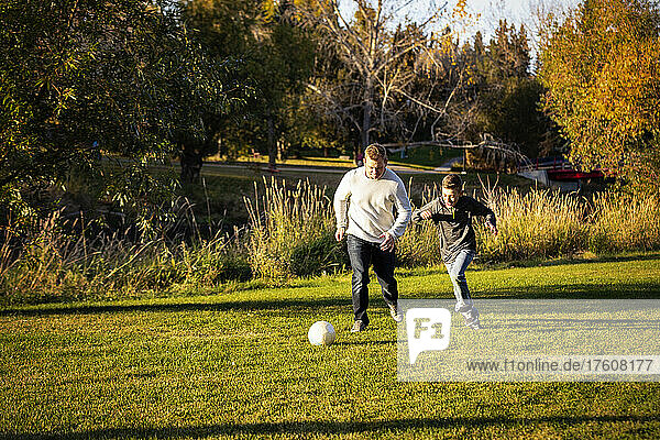 Vater spielt Fußball mit seinem Sohn in einem Park im Herbst; St. Albert  Alberta  Kanada